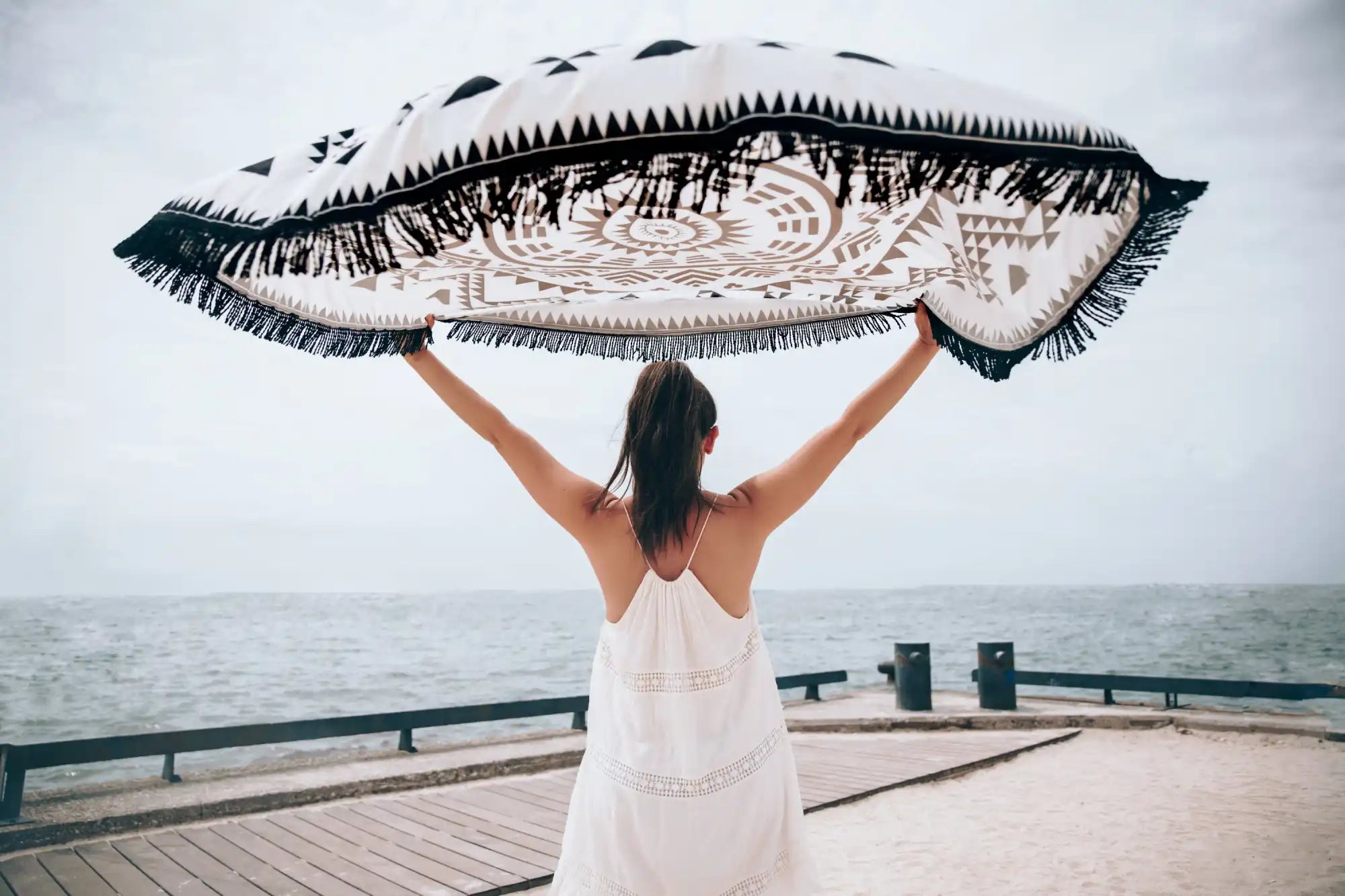 Round beach blanket with geometric patterns and fringe.